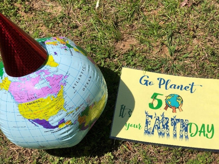 Globe with party hat and sign saying, “Go Planet, It’s Your 50th Earth Day.”